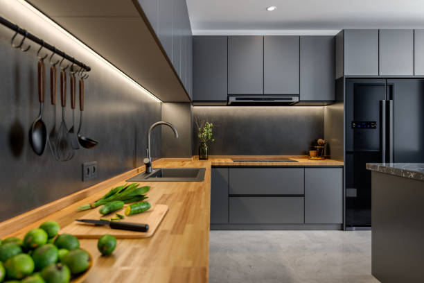 Kitchen with a modern design, featuring gray cabinetry, stainless steel appliances, and a wooden countertop. The space is illuminated with warm under-cabinet lighting, adding to the luxurious feel.