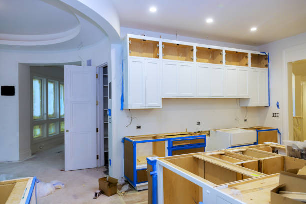 Workers are installing white cabinetry in modern kitchen renovation with an open layout design ample natural light.