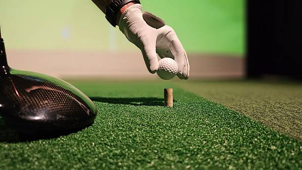 Practicing golf swing technique indoors with a driving range simulator in the evening